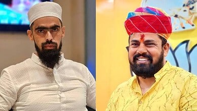 Two men in traditional attire, one with a white cap and the other with a red turban, smiling.