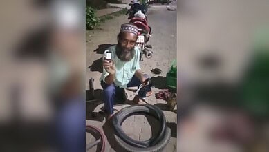 Man with a beard and traditional cap repairing a bicycle puncture outdoors.