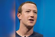 Mark Zuckerberg speaking at an event with a blue background.