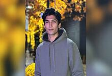 Pakistani cricketer Mohammad Hasnain in a grey hoodie outdoors during autumn.