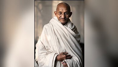 Mahatma Gandhi in traditional attire, sitting and smiling, reflecting on films he watched.