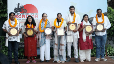 Group of people with marigold garlands holding awards at a mental health event.