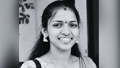 Smiling woman wearing traditional Indian attire and jewelry in black and white.