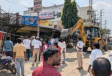 Road clearing operation with excavator and crowd on Moinabad–Chevella Road.