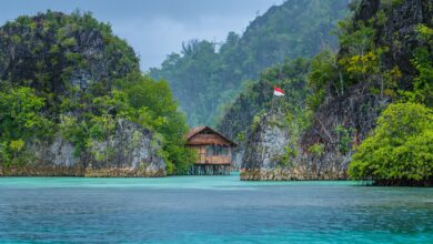 Bamboo Hut between some Rocks under Rain in Bay with Indonesian Flag, Pianemo Islands, Raja Ampat