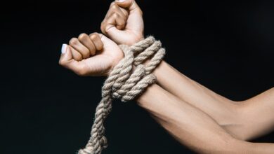 cropped shot of female hands bound with rope isolated on black