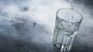 Last drops of pure water are poured into large glass cup