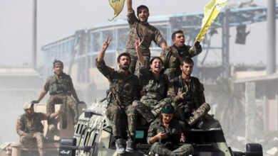 Kurdish militia ride atop military vehicles as they celebrate victory over Daesh in Raqqa, Syria