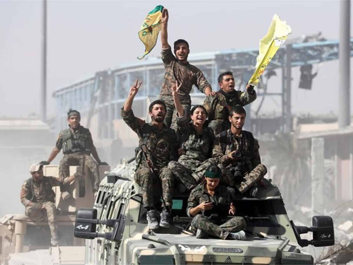 Kurdish militia ride atop military vehicles as they celebrate victory over Daesh in Raqqa, Syria