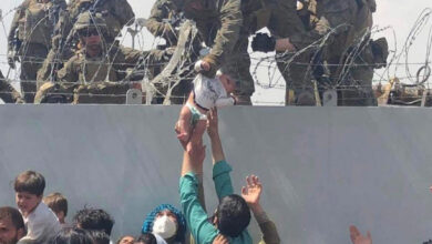 Baby passed over a wall at Kabul airport reunited with family