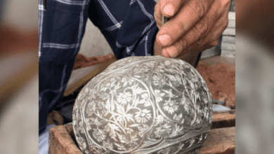 A Bidriware artisan carrying out silver inlay work on a hookah base.