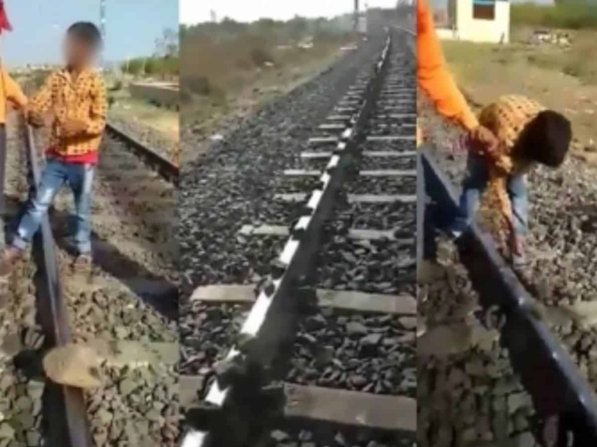 boy placing stones on railway track