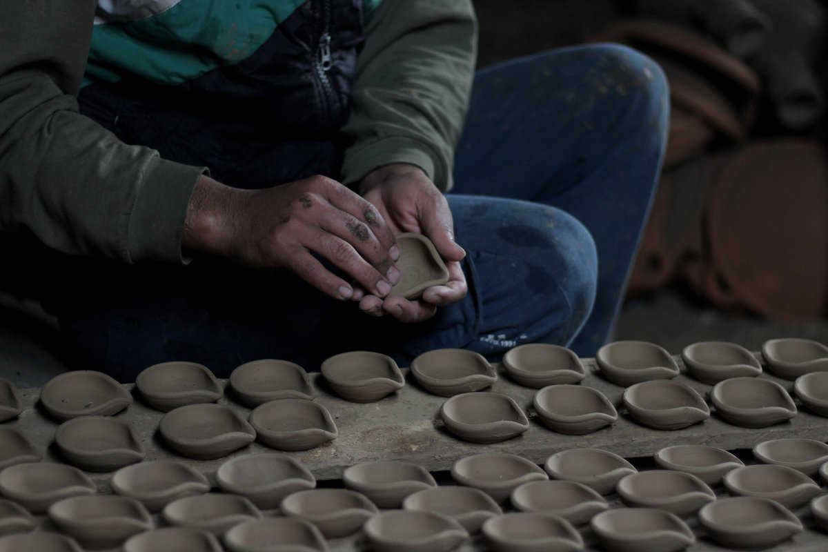 A potter clears oil lamps of dirt before putting them in ove to make them ready to use