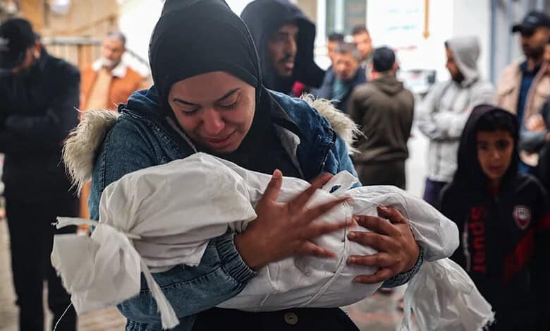 A Palestinian mother cries with the dead body of her baby