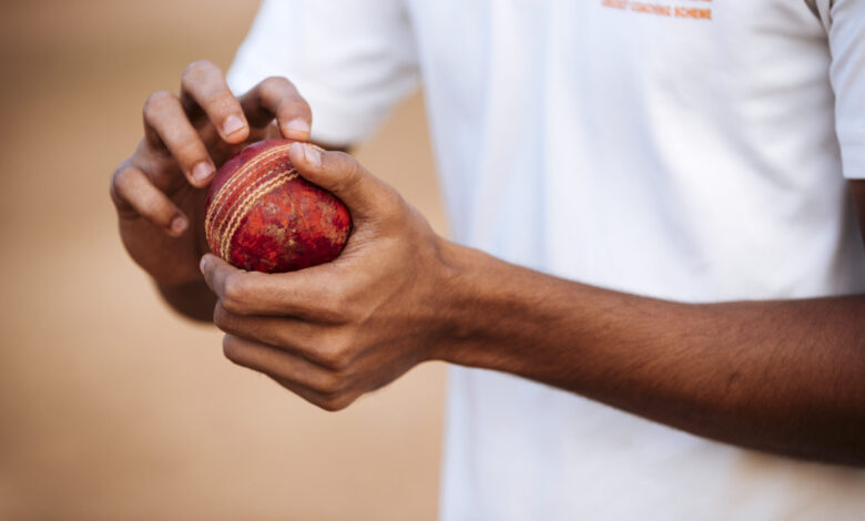 Cricketer holding a worn cricket ball ready to bowl