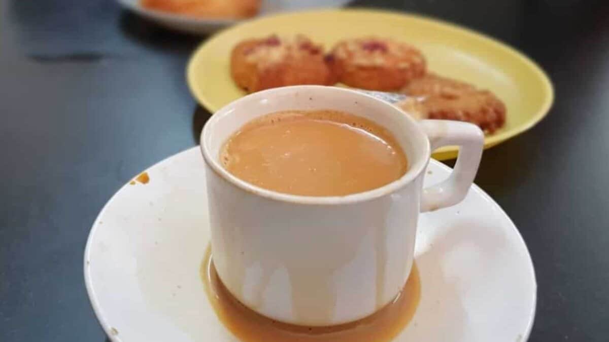 A cup of irani chai with biscuits in the background