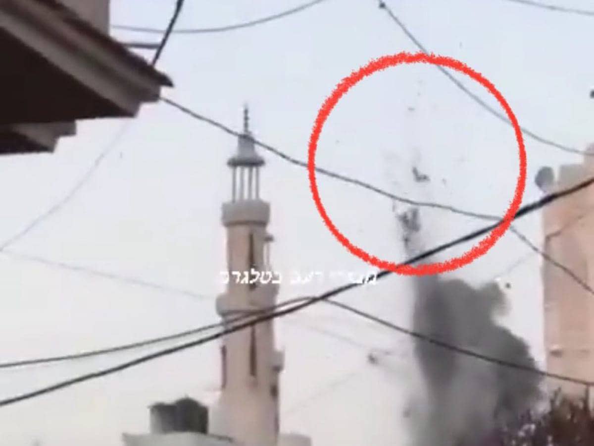 A screengrab from a viral video reportedly showing the aftermath of an Israeli missile strike in Gaza. The image features a mosque in the background, with a red circle highlighting what appears to be bodies being thrown into the air due to the explosion. Smoke is visible rising from the impact site, and electrical wires crisscross the foreground.