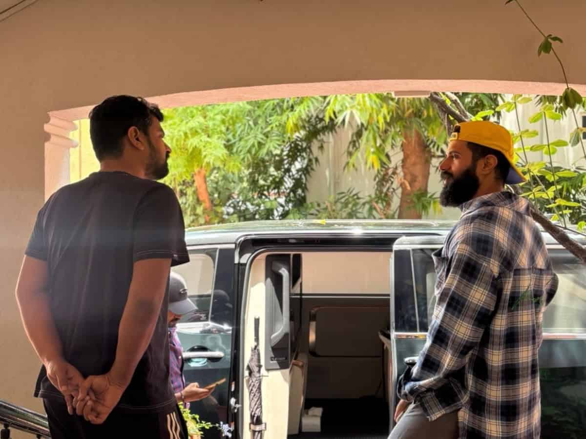 Two individuals stand outside a vehicle in a residential area