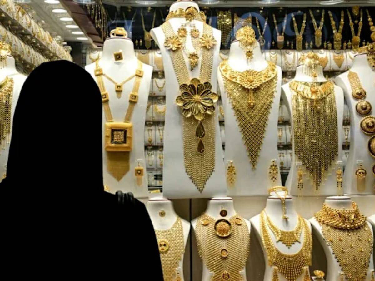 Woman in abaya looking at gold jewellery display in Dubai shop window