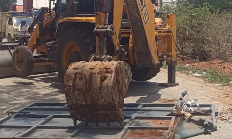 A JCB machine operated by HYDRAA demolishes an illegal gate blocking the road between Kandlakoya and Devrayanjal, clearing obstructions to restore access to National Highway 44.