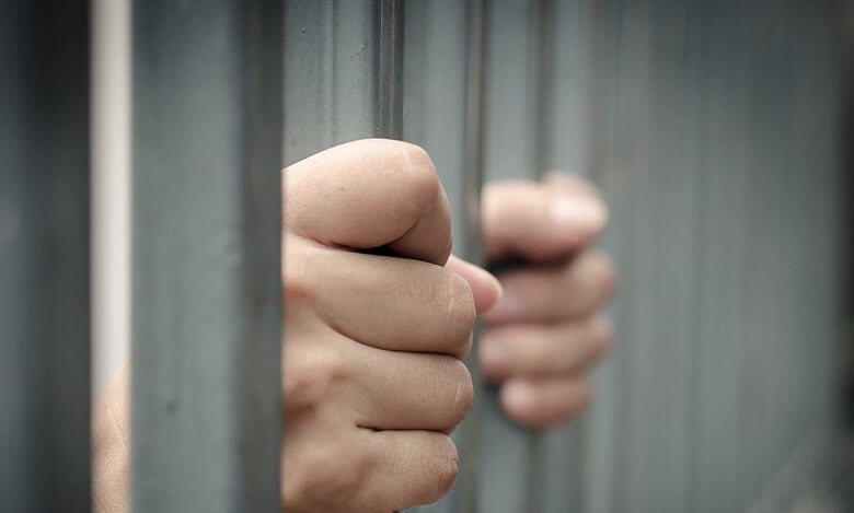 Representational Image of man holding prison bars