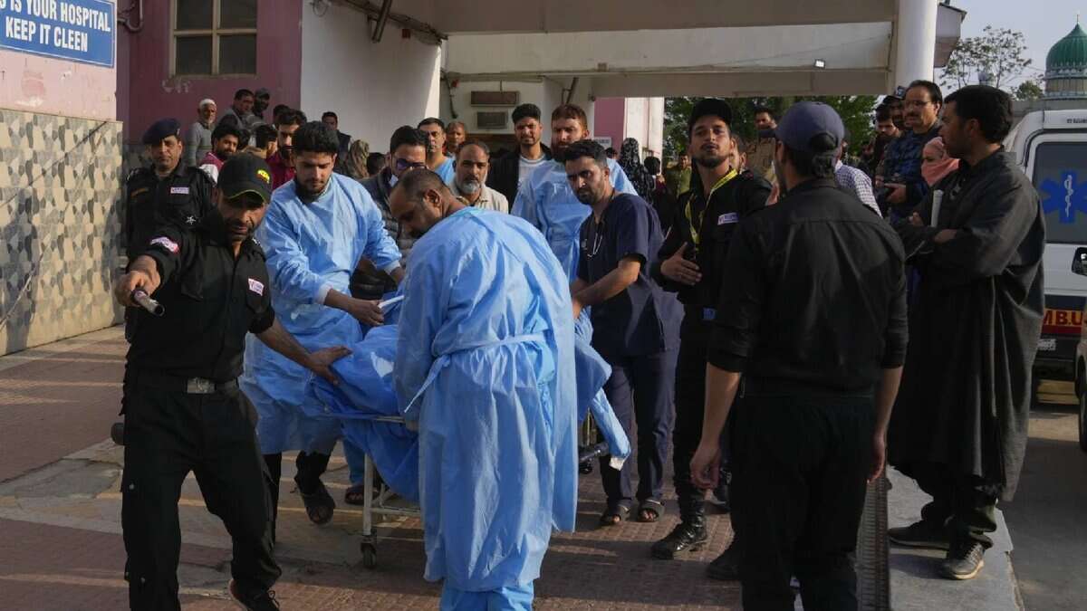 Paramedics and security personnel rush an injured individual into a hospital in Anantnag following the Pahalgam terror attack, amid a crowd of concerned onlookers.