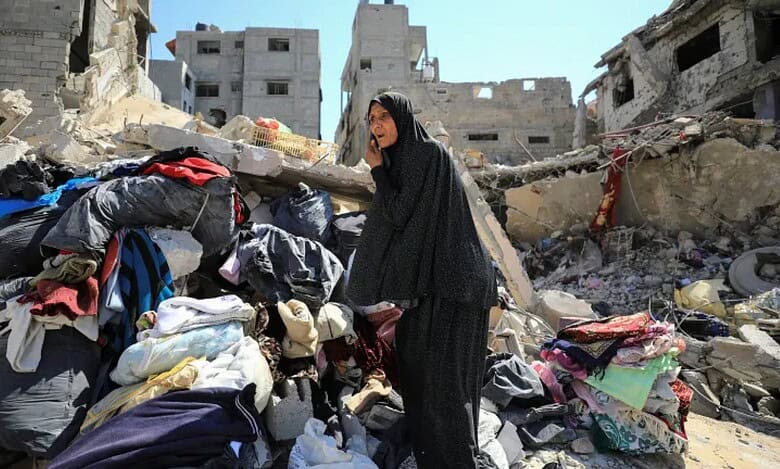 Palestinian woman stands on rubble, inspecting damage in Shujayea, Gaza, after Israeli forces withdraw following ground operation.
