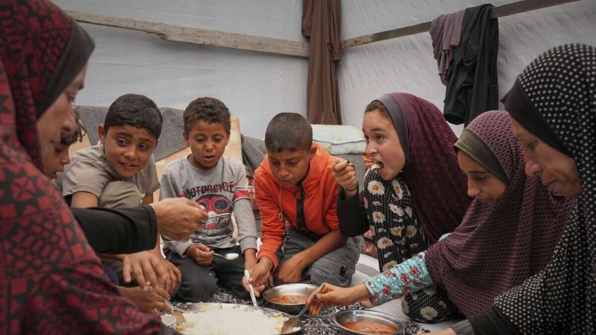 The Al-Najjar family shares a meal of peas and rice in their tent in Muwasi, near Khan Younis, southern Gaza Strip, Friday, April 25.