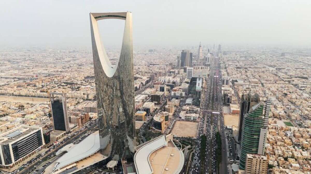 Aerial view of Riyadh city skyline, Saudi Arabia, featuring the iconic Kingdom Centre Tower and surrounding modern skyscrapers on a hazy day.
