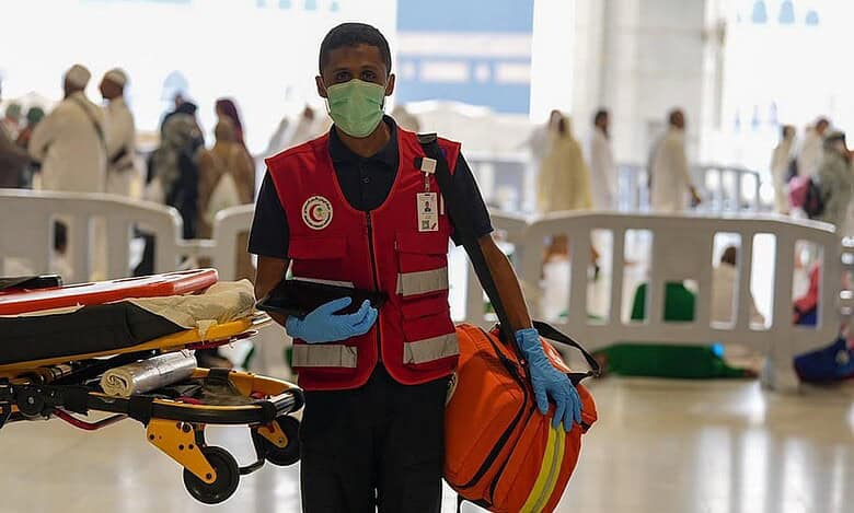 Saudi Red Crescent medic with stretcher and emergency bag at Grand Mosque.