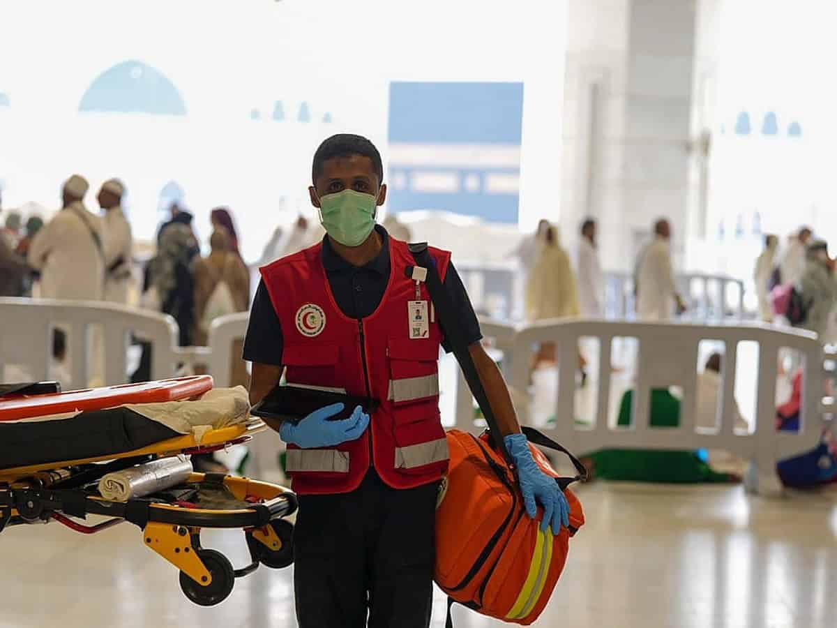 Saudi Red Crescent medic with stretcher and emergency bag at Grand Mosque.
