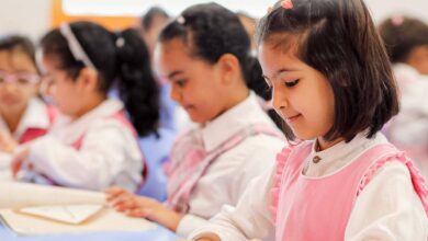 Young Saudi girls in a classroom wearing pink uniforms, engaged in learning activities at a Saudi school.