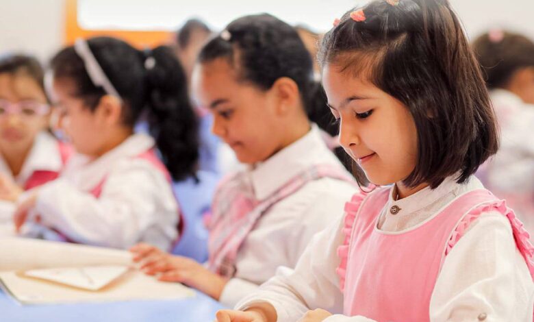Young Saudi girls in a classroom wearing pink uniforms, engaged in learning activities at a Saudi school.
