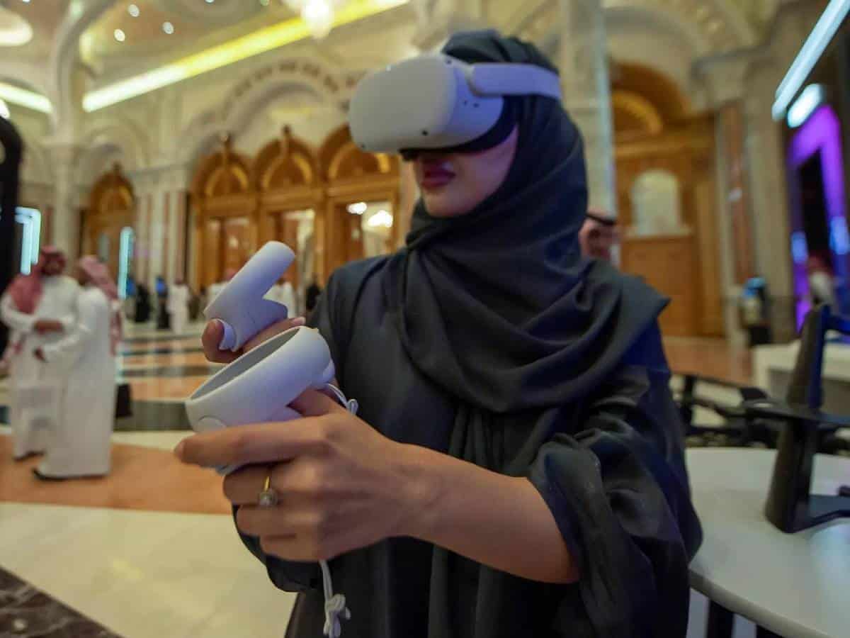 Saudi woman wearing VR headset and using controllers at a tech event in Riyadh