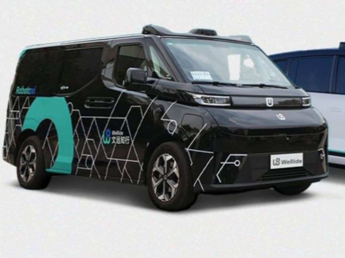 Self-driving taxi by WeRide, a black autonomous vehicle with futuristic hexagonal patterns, showcased with 'Robotaxi' branding. The vehicle, designed for urban smart mobility, features advanced sensors on its roof for autonomous navigation.