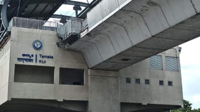 Concrete structure of Tarnaka Junction metro station with signage in Telugu and English, elevated platform above.