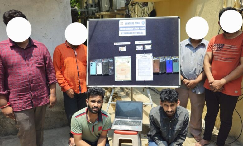 Six individuals, including two kneeling in front, are seen near a display board labeled "Commissioner's Task Force, Hyderabad City Police, Central Zone." The board shows seized items including smartphones, fake Aadhaar cards, a Bangladesh passport copy, and forged birth certificates