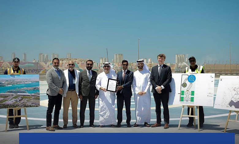 Officials pose at the site of the UAE’s first hybrid heliport at Zayed Port, Abu Dhabi, with development plans displayed on easels.
