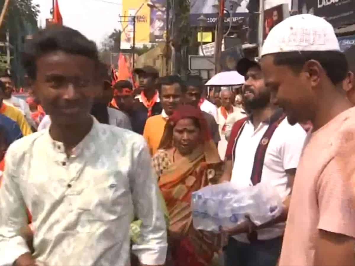 A Ram Navami devotee smiles at a Muslim man as he accepts a bottle of water from him in West Bengal on Sunday