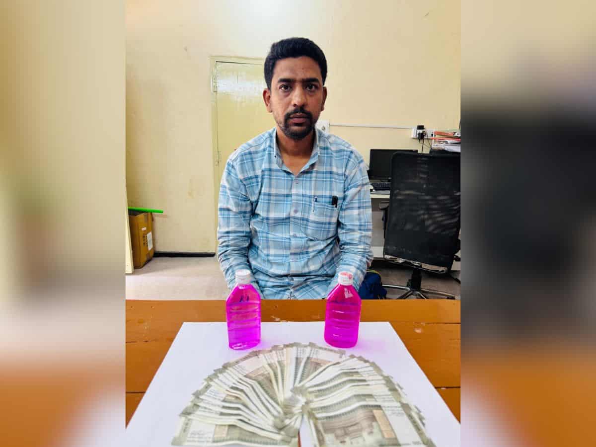The image shops a man with stack of Indian rupees in front of him