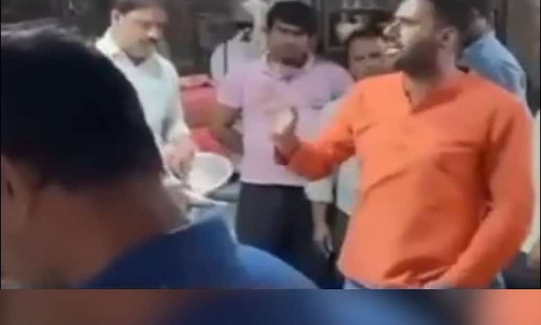 A man in saffron clad clothes talks to fish sellers in East Delhi on April 9, 2025