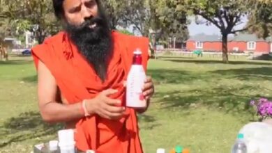 The image displays Ramdev baba in saffron clothing holding a drink