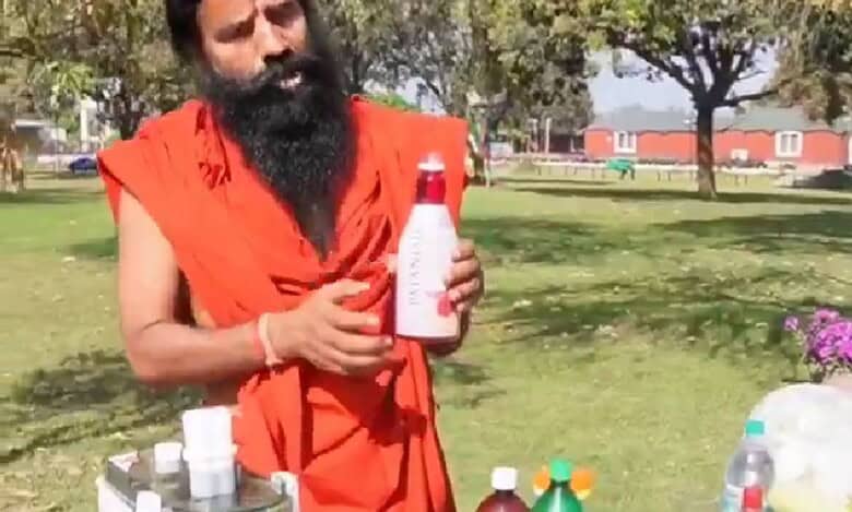 The image displays Ramdev baba in saffron clothing holding a drink