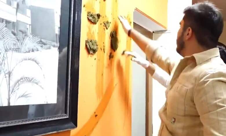 The image displays a student applying cow dung at the DU principal's office. April 16, 2025