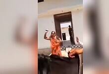 The image shows a woman in an orange saree throwing stones