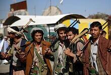 Armed Houthi fighters stand in a row in Sanaa, Yemen, carrying rifles and traditional Yemeni daggers.