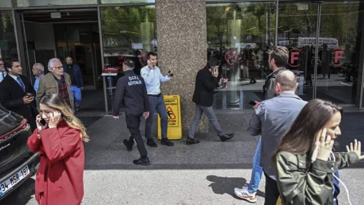 People evacuate a building in Istanbul, Turkey, in panic after a 6.2 magnitude earthquake on April 23, 2025. Several individuals are seen using their phones, likely contacting loved ones, while security personnel assist in managing the situation.