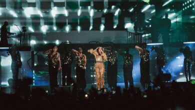 Jennifer Lopez performs live at the 2025 Saudi Arabian Grand Prix concert in Jeddah, centre stage in a gold embellished outfit, surrounded by backup dancers in matching black and gold costumes, with dramatic lighting and digital visuals in the background.