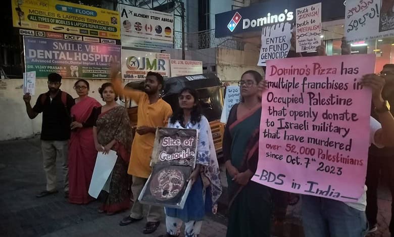 A group of protesters on May 10 stand outside a Domino’s outlet in India, holding signs in solidarity with Palestine. One sign reads, "Slice of Genocide?"