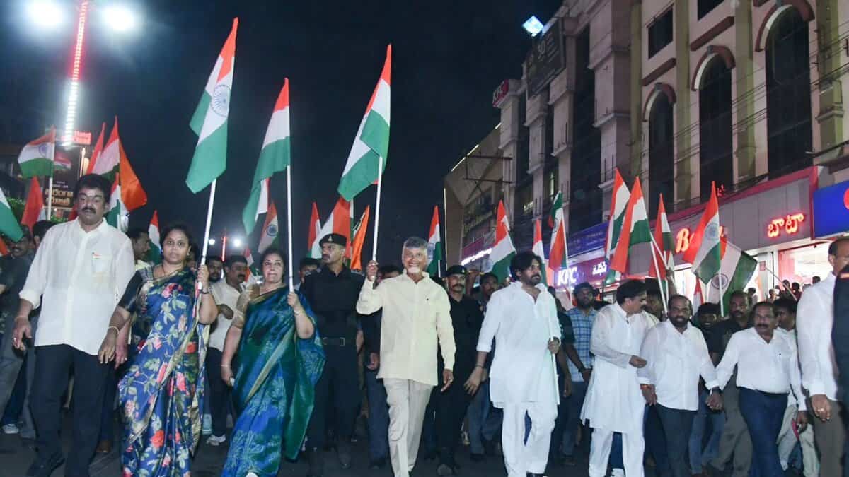 A large group marches at night holding Indian flags, including leaders and civilians, celebrating national unity and pride.